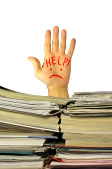 someone raising hand behind a pile of documents and asking for help